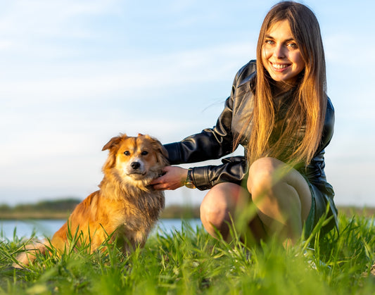 a woman kneeling down next to a brown dog