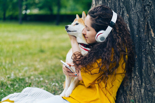 a woman sitting on the grass with a dog and headphones